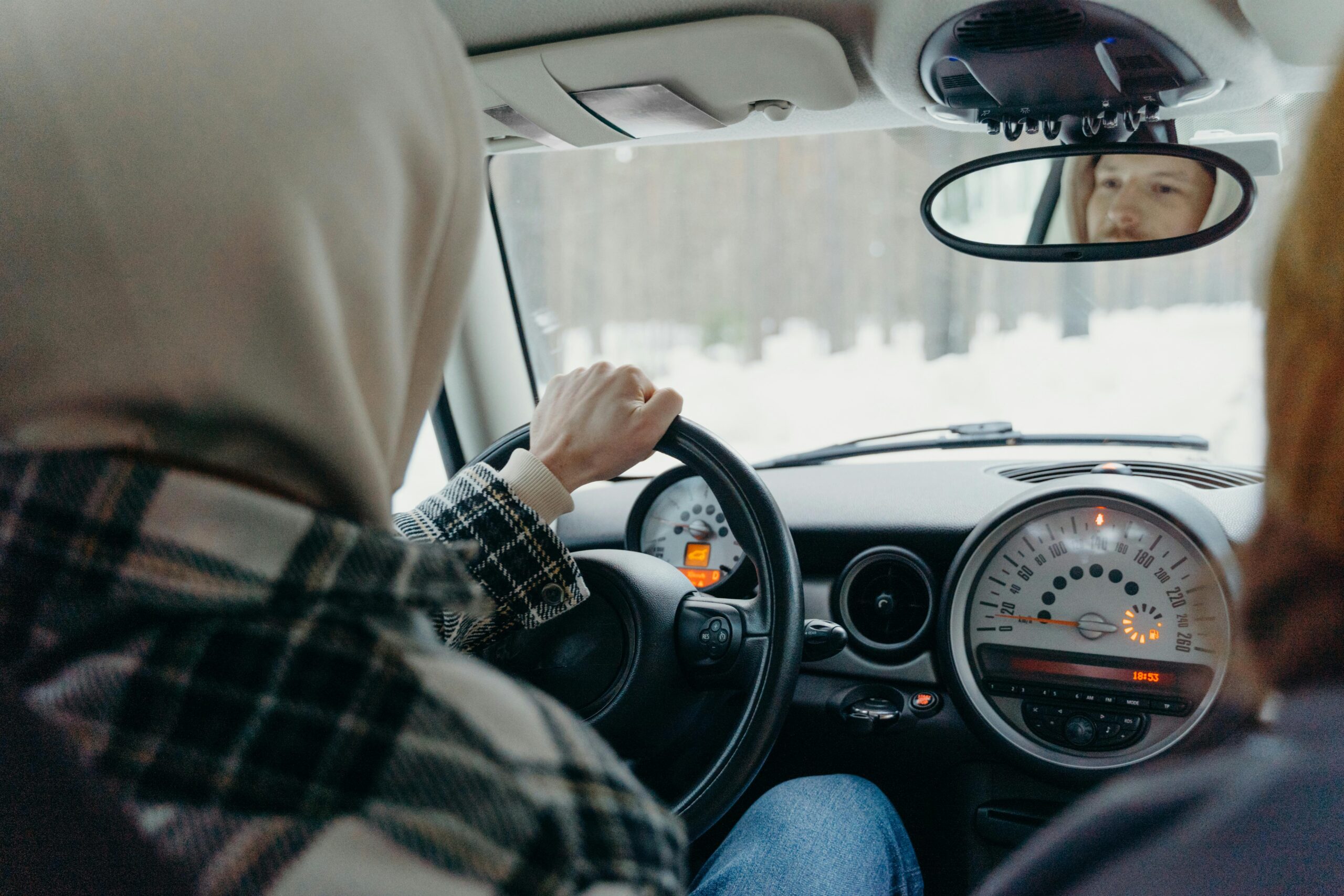 Driving through a snowy forest in winter, capturing the serene landscape from a car's interior.